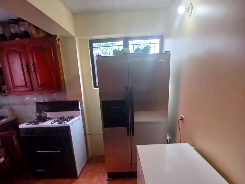 The kitchen with a gas stove, wooden cabinets, a large double-door refrigerator and a chest freezer